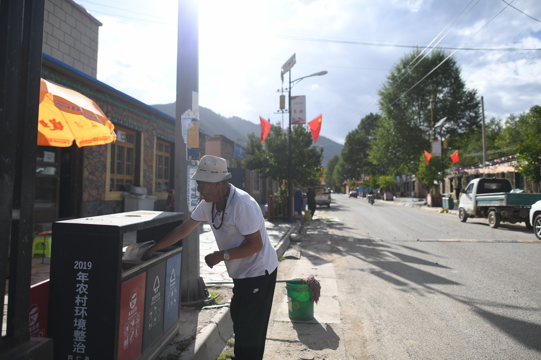 9月1日，扎毛村村民完德卡將垃圾投放至垃圾桶。